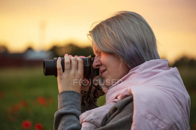 Jeune femme prenant des photos au coucher du soleil — Photo de stock