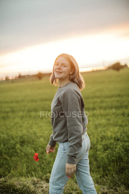 Молода жінка ходить у полі на заході сонця — стокове фото