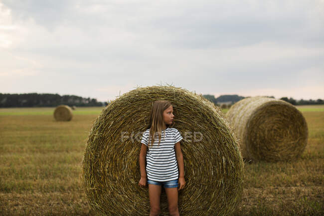 Chica por paca de heno en la granja - foto de stock