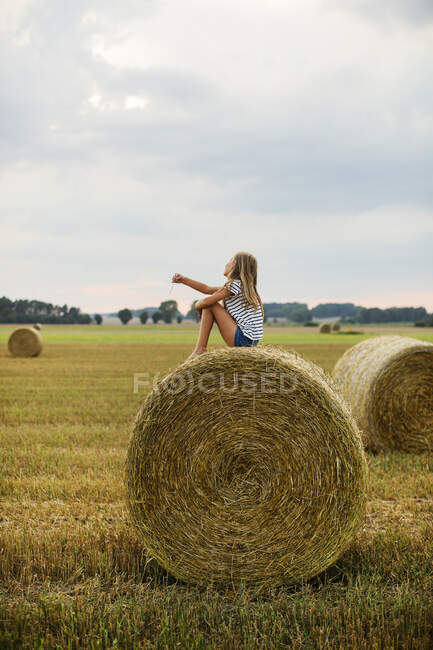 Девушка сидит на тюке сена — стоковое фото