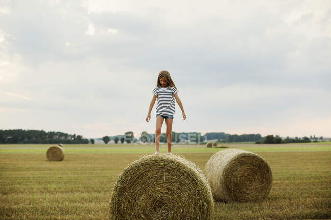 Girl standing on hay bale — Stock Photo