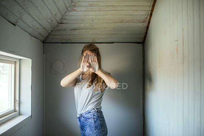 Frau verdeckt ihr Gesicht durch Fenster — Stockfoto