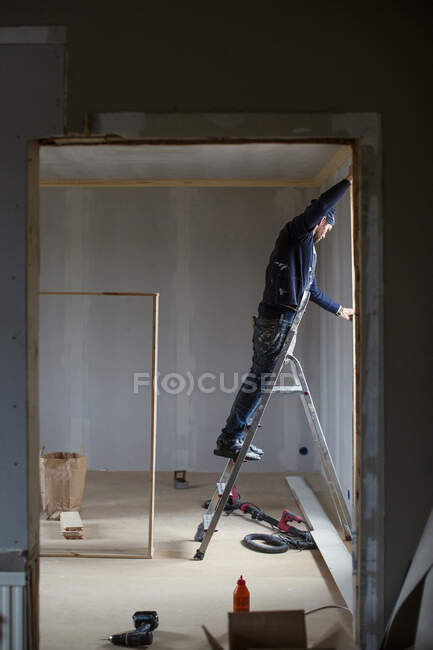 Человек на лестнице во время ремонта дома — стоковое фото