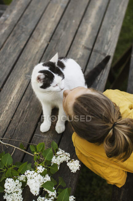 Girl kissing her cat on deck — Stock Photo