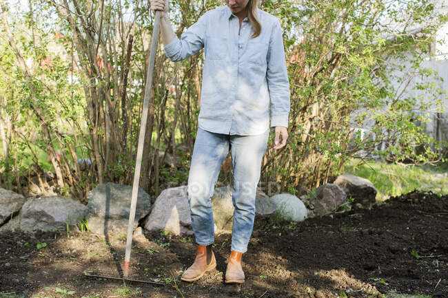 Frau hält Harke bei Gartenarbeit in der Hand — Stockfoto