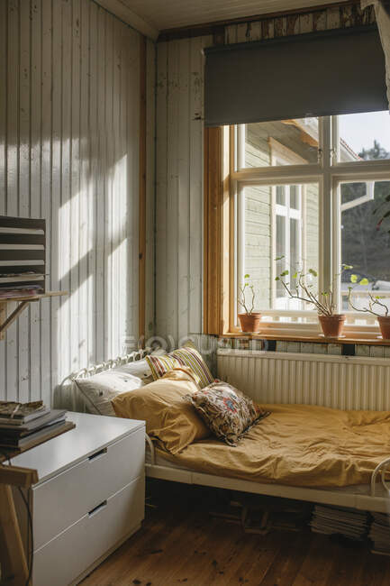 Кровать у окна с горшечными растениями — стоковое фото