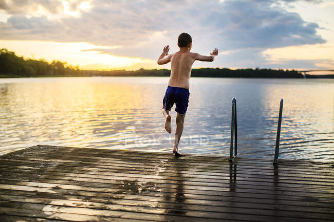 Garçon plongeant dans le lac au coucher du soleil — Photo de stock