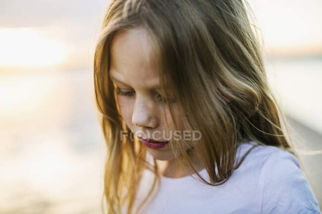 Chica por lago durante la puesta del sol - foto de stock