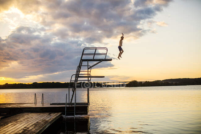 Хлопчик пірнає в озеро на заході сонця. — стокове фото