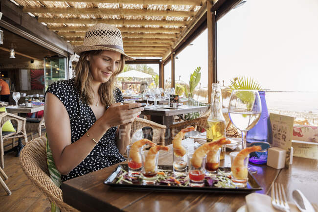 Mujer sentada en restaurante con cócteles de camarones - foto de stock