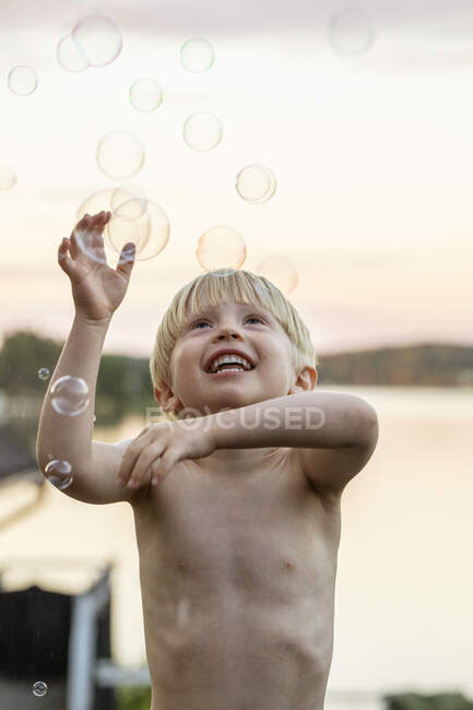Хлопчик грає з бульбашками на заході сонця — стокове фото