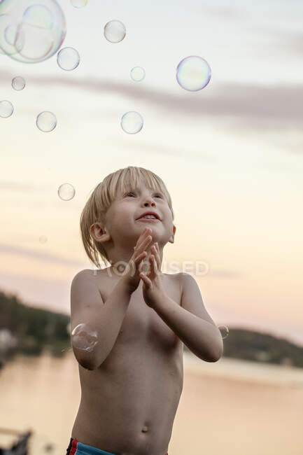 Menino brincando com bolhas ao pôr do sol — Fotografia de Stock