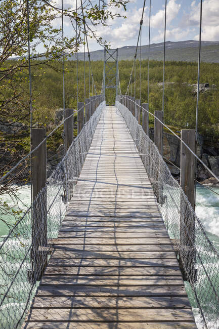 Holzbrücke und Äste über Fluss — Stockfoto