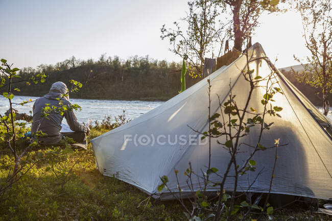 Man camping with tent by river — Stock Photo