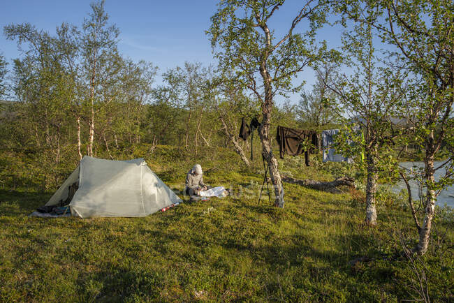Человек сидит в палатке во время похода — стоковое фото