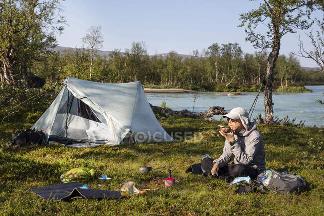 Uomo campeggio con tenda sul fiume — Foto stock