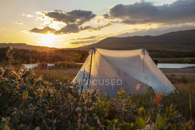 Tienda de campaña por las colinas durante la puesta del sol - foto de stock