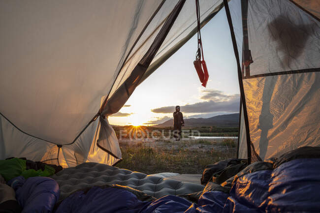 Человек идет в палатку на закате — стоковое фото