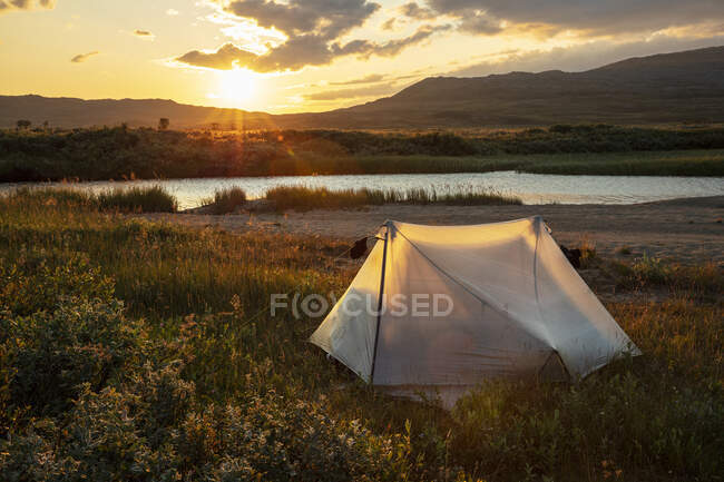 Tenda por colinas durante o pôr do sol — Fotografia de Stock
