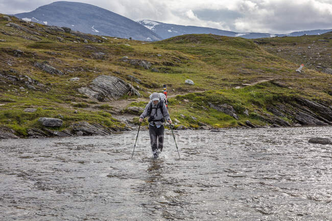 L'uomo guadare attraverso il fiume durante le escursioni — Foto stock