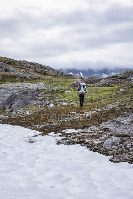 Homem caminhando por rochas na montanha — Fotografia de Stock