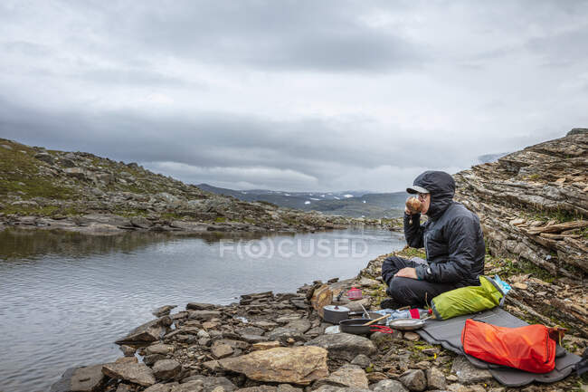 Hombre acampando en rocas por río - foto de stock