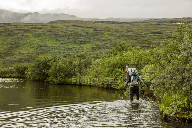 Чоловік блукає по річці під час пішохідного туризму — стокове фото