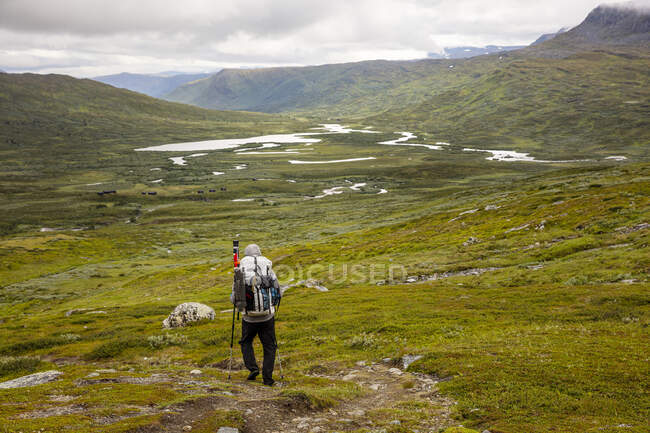Человек с рюкзаком, идущий по холму — стоковое фото
