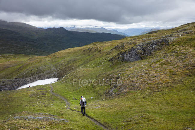 Hombre senderismo en el camino sobre la colina - foto de stock