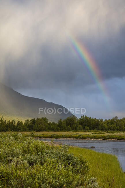 Rainbow and clouds over mountain — Stock Photo