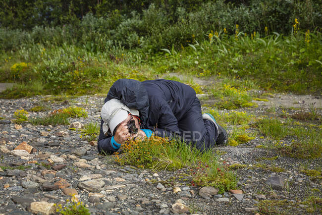 Мужчина фотографирует цветы во время похода — стоковое фото