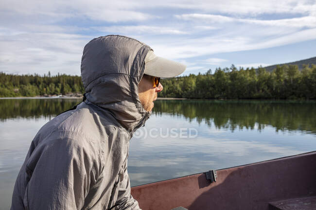 Hombre con capucha sentado en canoa - foto de stock