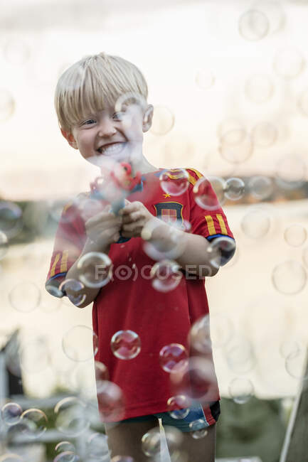 Усміхнений хлопчик грає з бульбашками — стокове фото