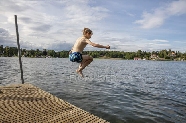 Мальчик в воздухе во время погружения в озеро — стоковое фото