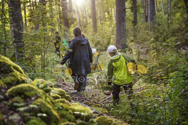 Madre e hijo llevando cestas en el bosque - foto de stock