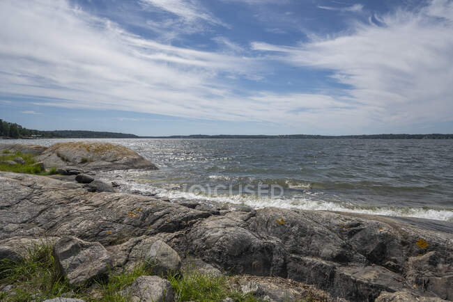 Rocks by lake under clouds — Stock Photo