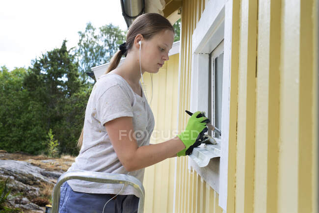 Adolescente menina pintura janela da casa — Fotografia de Stock
