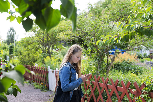 Teenage girl text messaging in park — Stock Photo