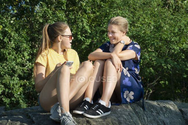 Mujer y adolescente sentado en la roca - foto de stock