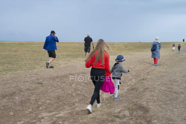 Family walking up hill by coast — Stock Photo