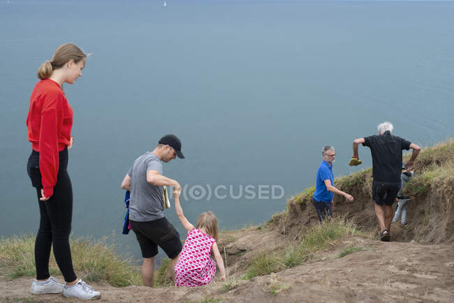 Family climbing hill by coast — Stock Photo