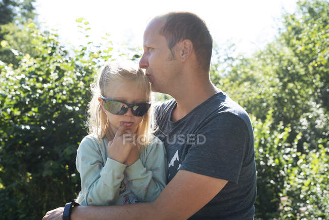 Chica con gafas de sol sentado con su padre - foto de stock