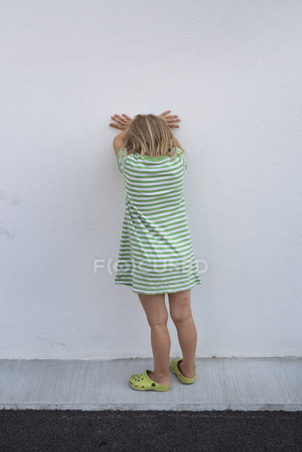 Mädchen in grün gestreiftem Kleid lehnt an Wand — Stockfoto