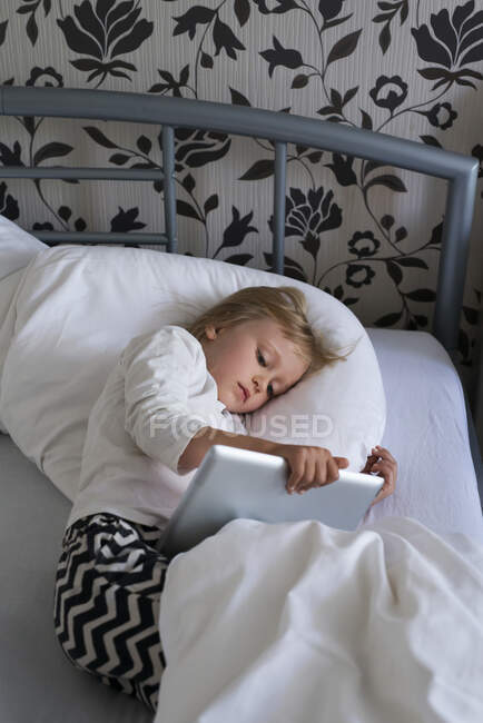 Ragazza che utilizza tablet digitale a letto — Foto stock