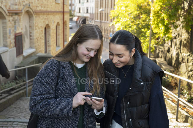 Молоді жінки використовують смартфон на міській вулиці — стокове фото