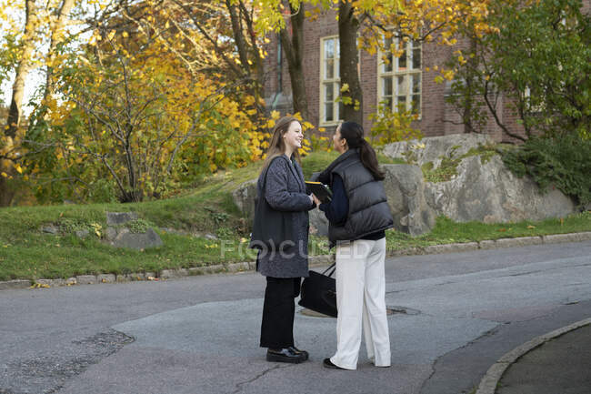 Mujeres jóvenes hablando en la calle de la ciudad - foto de stock