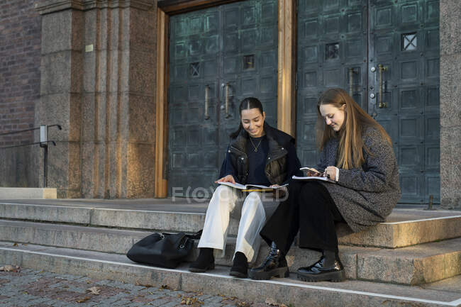 Mujeres jóvenes estudiando en escalones - foto de stock