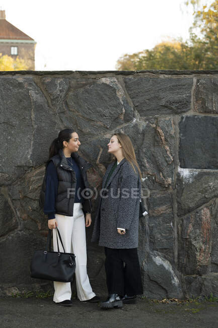 Молодые женщины разговаривают у стены — стоковое фото
