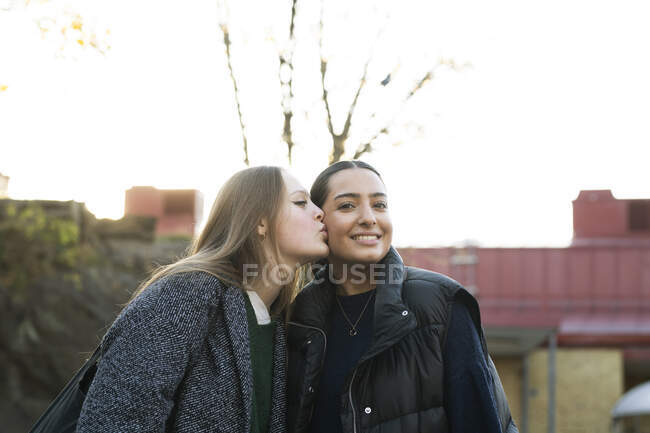 Jovem mulher beijando a bochecha de seu amigo — Fotografia de Stock