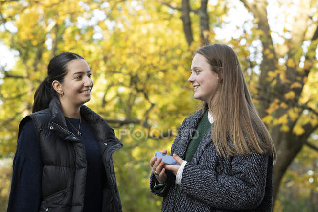 Mujeres jóvenes sonrientes junto a los árboles de otoño - foto de stock